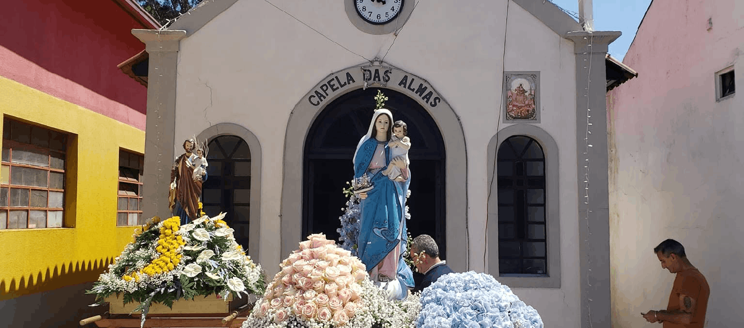 Capela das Almas com andores floridos diante da fachada, incluindo Nossa Senhora com o Menino Jesus e São José segurando o Menino Jesus.
