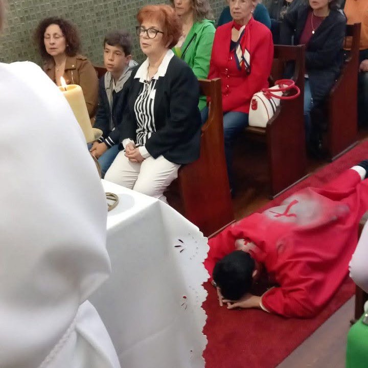 Consagração de Dom Carlos Fonseca, Lourosa (Santa Maria da Feira), 24 de abril de 2023 - clérigo de vestes vermelhas prostrado diante do altar enquanto a congregação observa